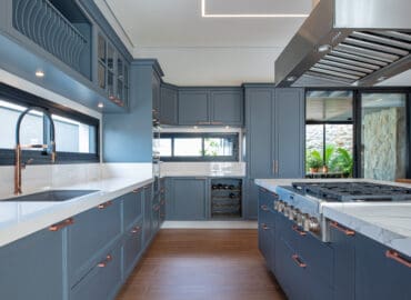 Cozinha em estilo provençal, com armários na cor azul, bancada revestida em Silestone na cor branca